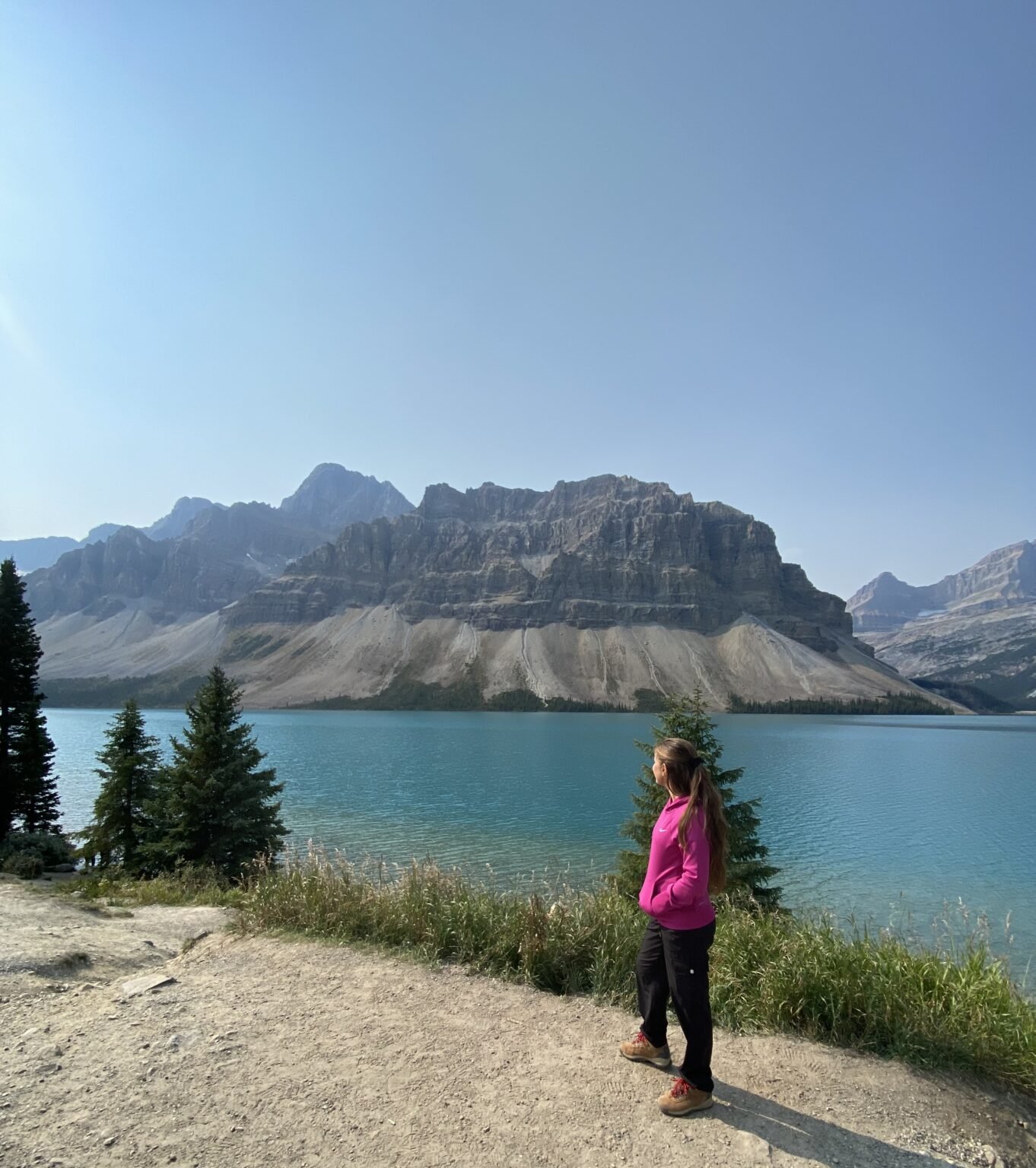la mujer está de espaldas a la cámara y en el fondo se ve el lago Bow y las montañas rocosas canadienses