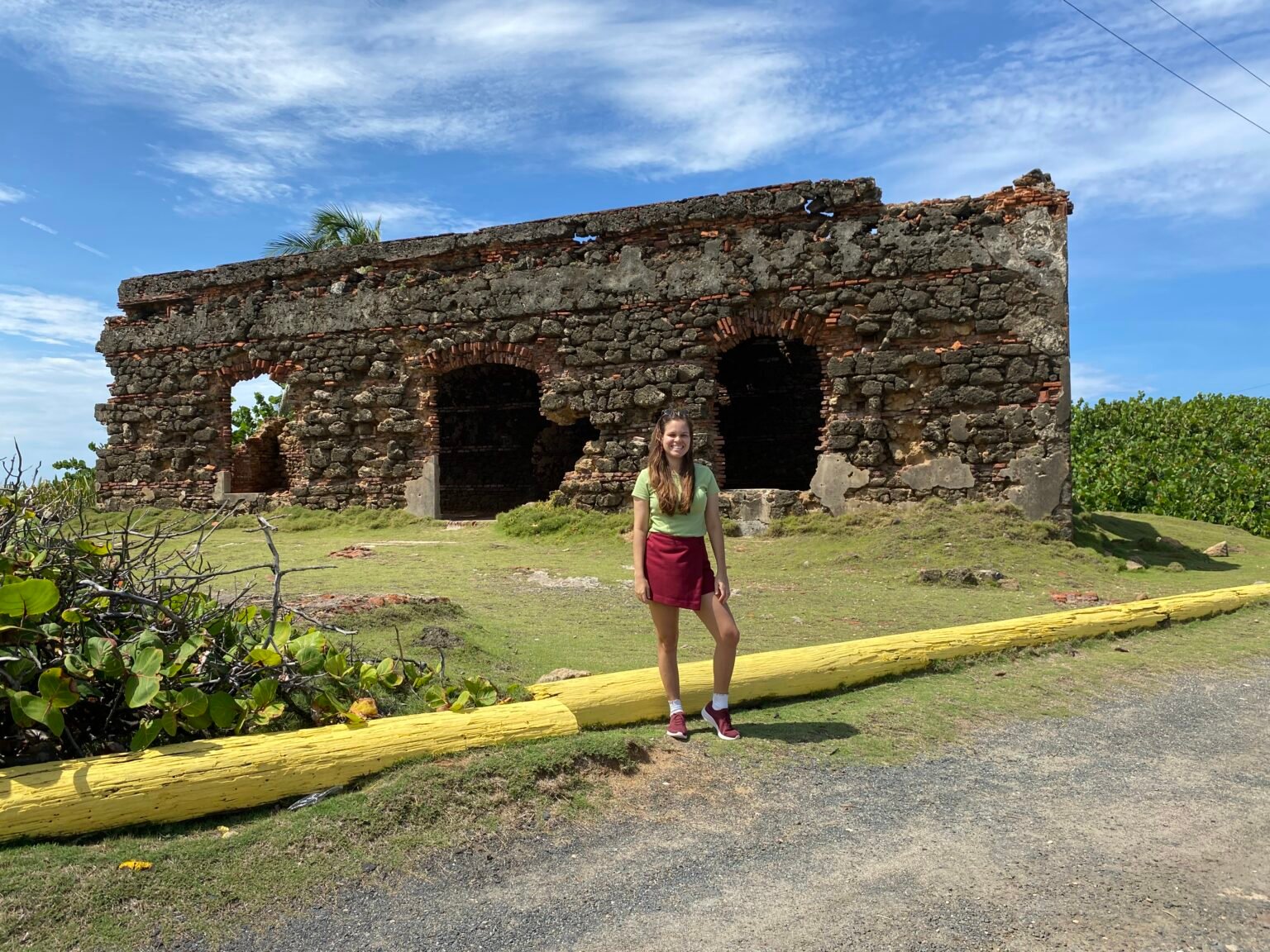 mujer de pie frente a las ruinas del antiguo leprocomio