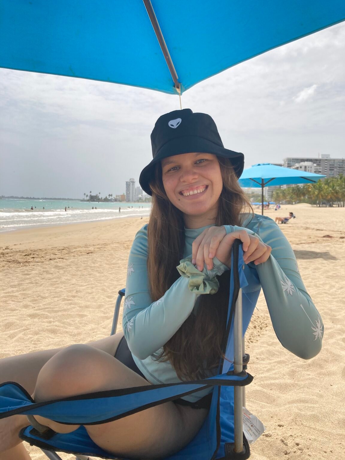 mujer sentada en una silla de playa, bajo una sombrilla de playa en la playa de isla verde