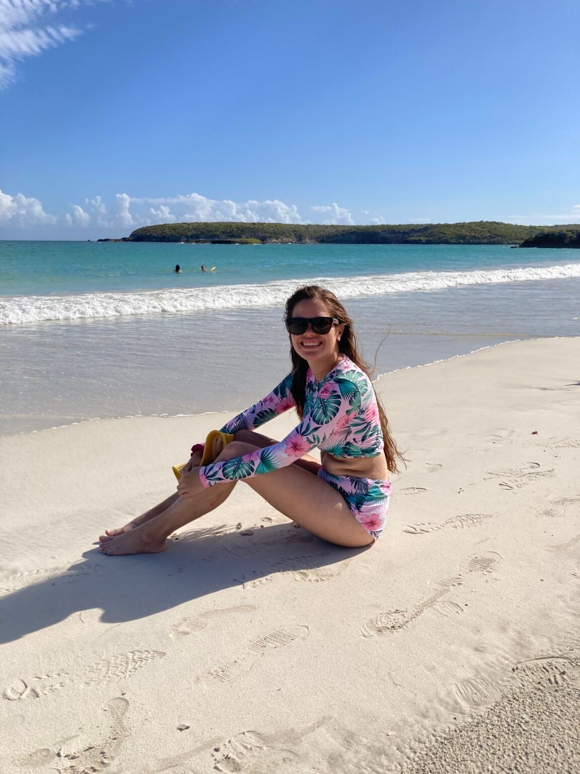 mujer con gafas y en traje de baño sentada en la arena blanca de playa la chiva en vieques