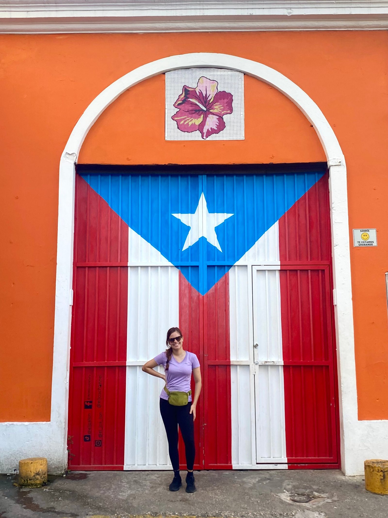 La mujer está de pie frente a un mural de la bandera de Puerto Rico en la Calle Imperial del Viejo San Juan.