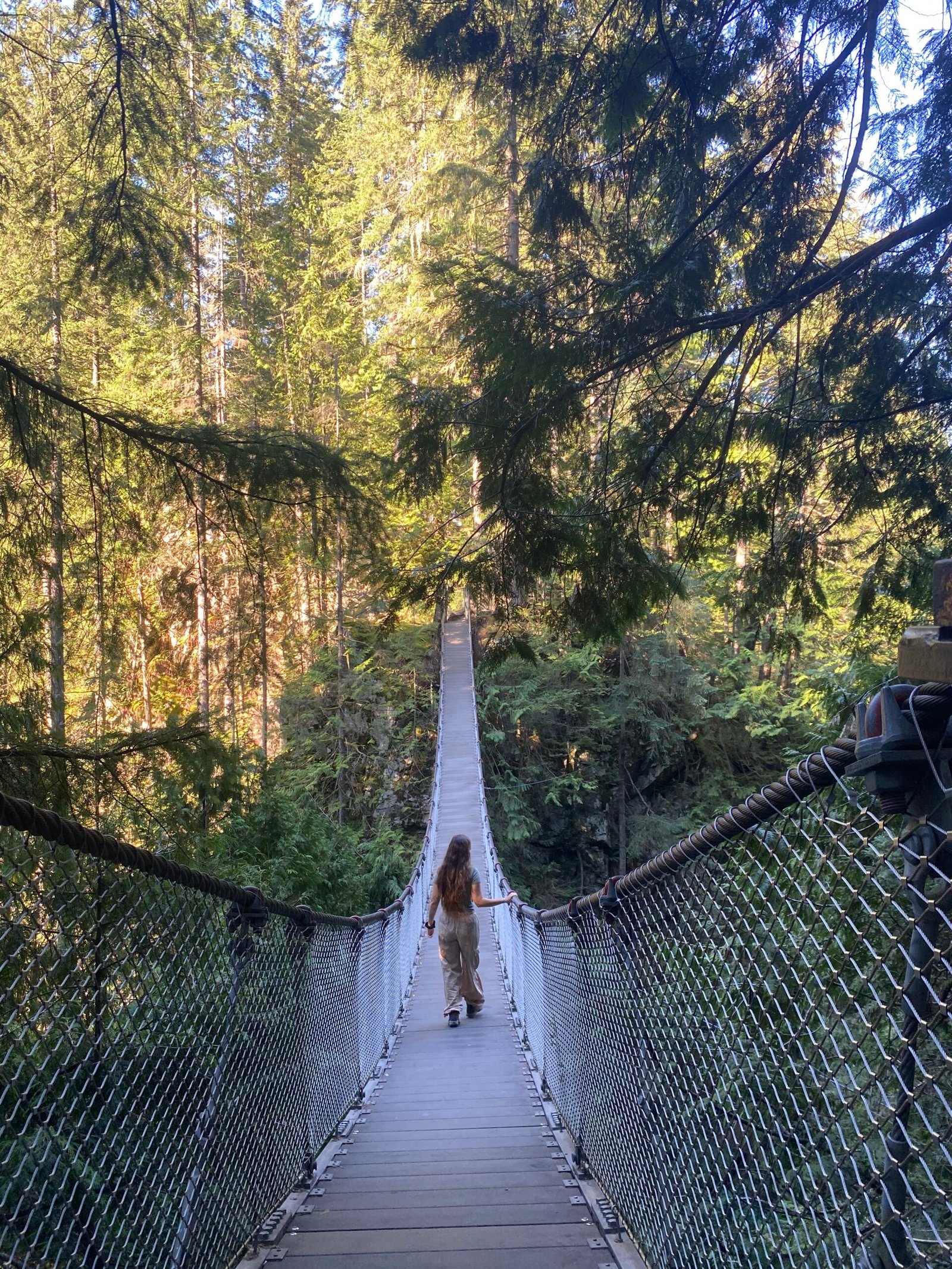 La mujer está cruzando el puente colgante del cañón Lynn.