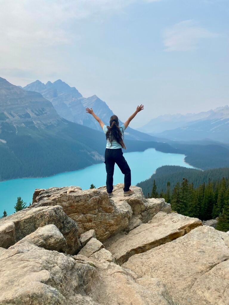 mujer de pie en un mirador con vista al Lago Peyto en el Parque Nacional Banff, Canadá