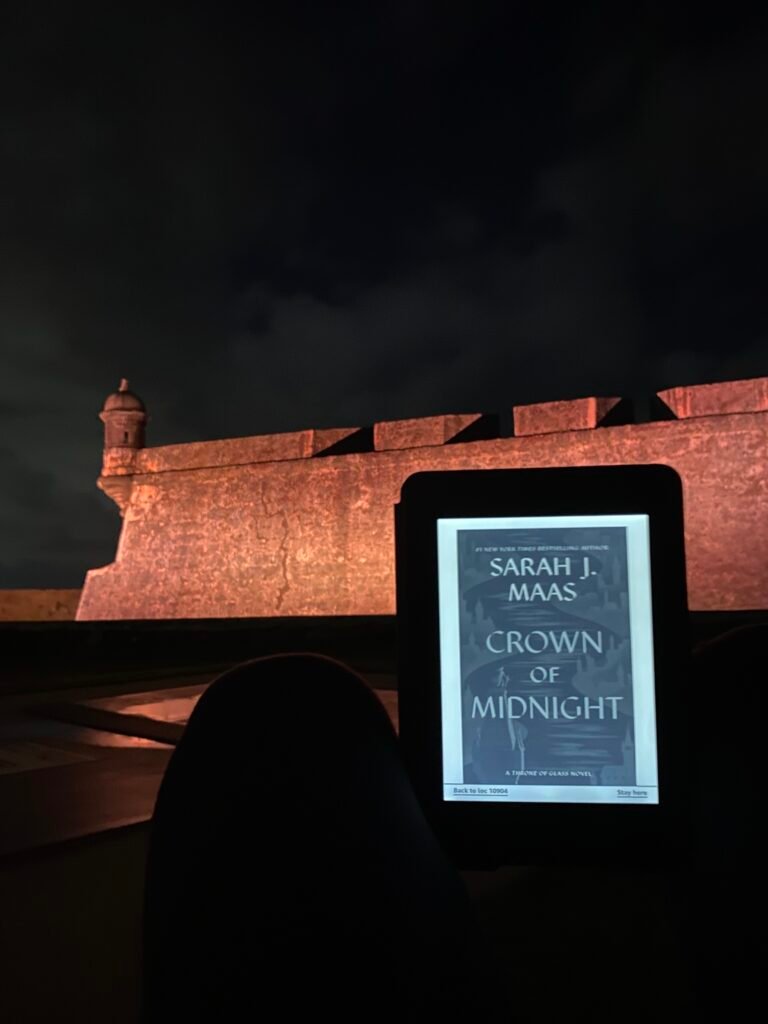 la mujer está leyendo Crown of Midnight en un kindle en el Morro de noche