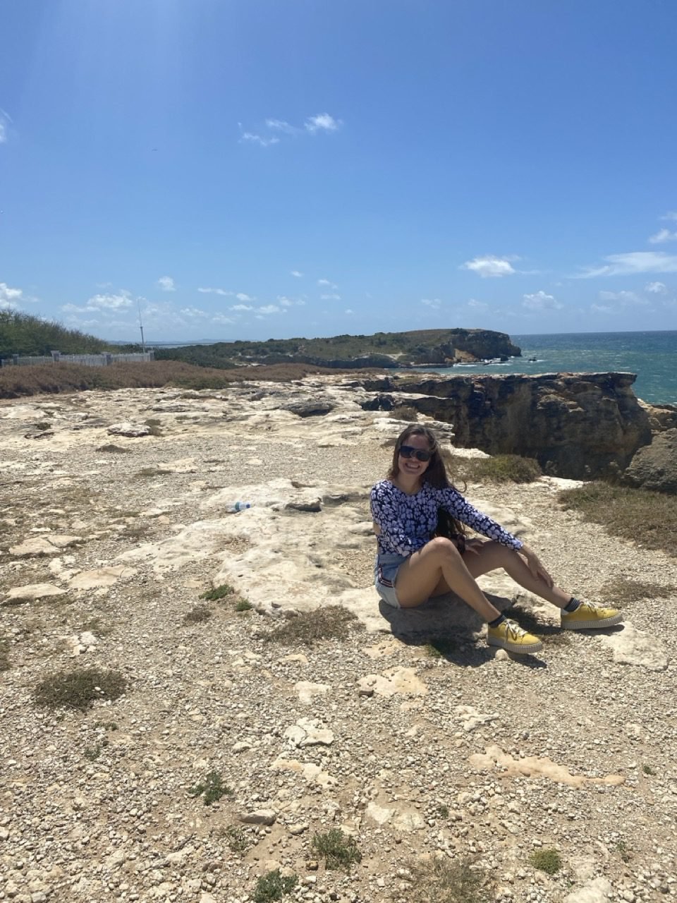 una joven sentada a la orilla de los acantilados de cabo rojo