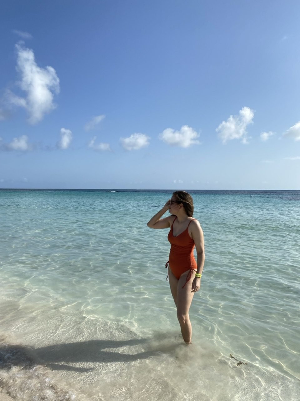 La mujer posa a la orilla de la Playa Flamenco en Culebra, vistiendo un traje de baño completo color terracotta.