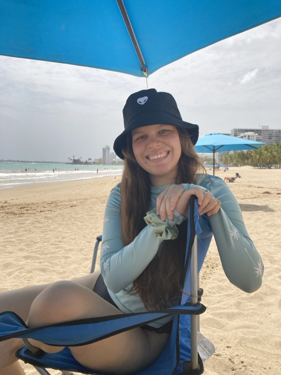 mujer sentada en una silla de playa, bajo una sombrilla de playa en la playa de isla verde