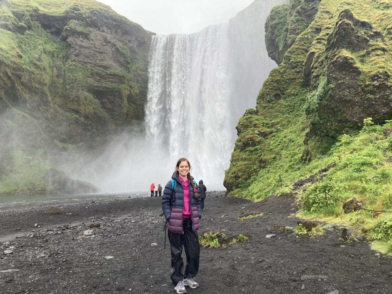 la joven esta de pie frente a la cascada Skogafoss