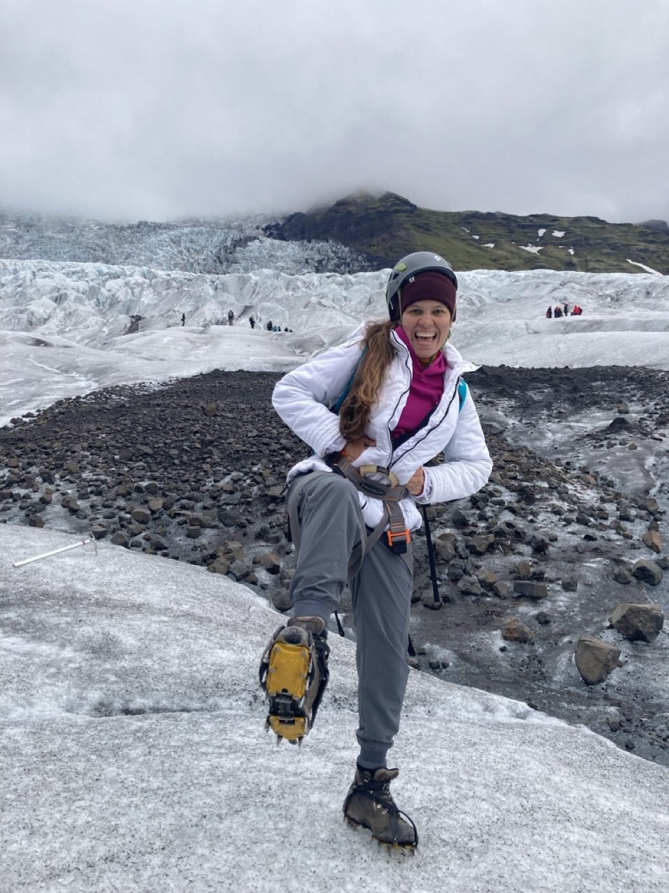 La joven sonríe para una foto en el glaciar Vatnajökull en Islandia, rodeada de hielo y roca